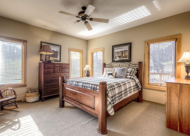 bedroom with ceiling fan, light colored carpet, and multiple windows