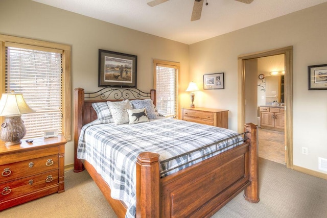 bedroom with ensuite bathroom, ceiling fan, and light colored carpet