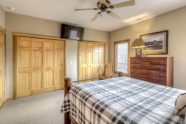 carpeted bedroom featuring ceiling fan and multiple closets