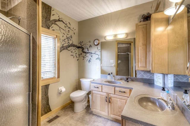 bathroom with tasteful backsplash, tile patterned flooring, toilet, vanity, and a shower with shower door