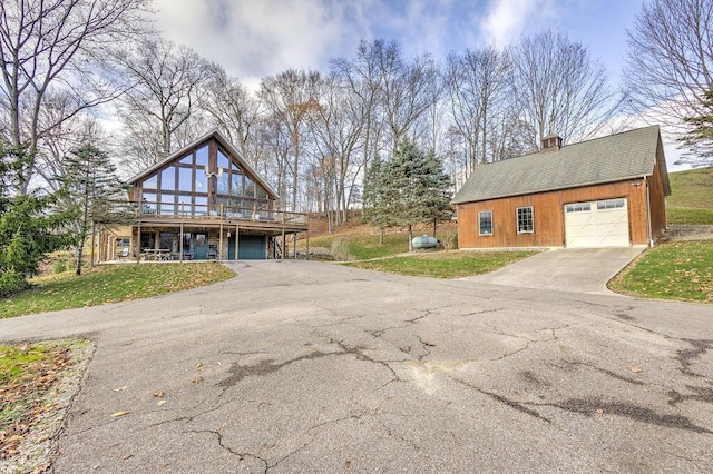 view of side of property with a garage, a lawn, an outdoor structure, and a wooden deck