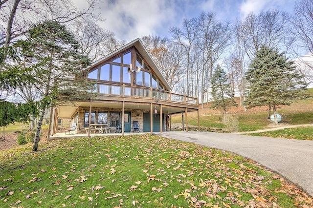 view of front of property with a deck, a patio, and a front lawn