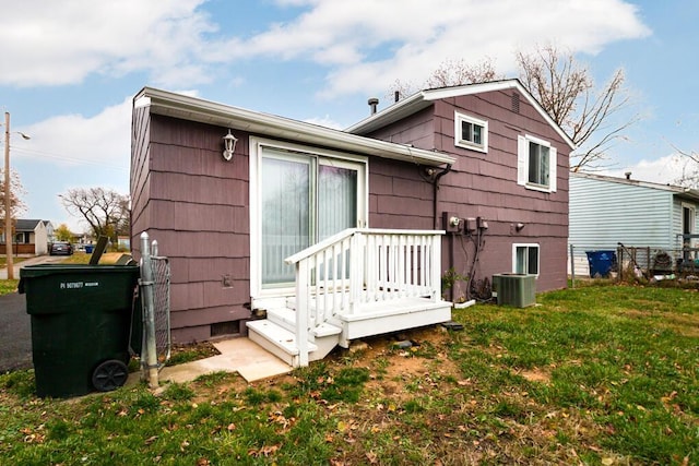 back of house with cooling unit and a lawn