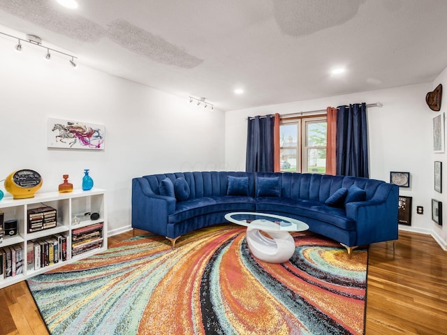 living room with a textured ceiling, rail lighting, and hardwood / wood-style flooring