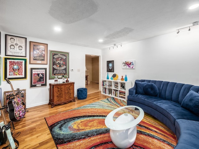 living room featuring wood-type flooring, a textured ceiling, and track lighting