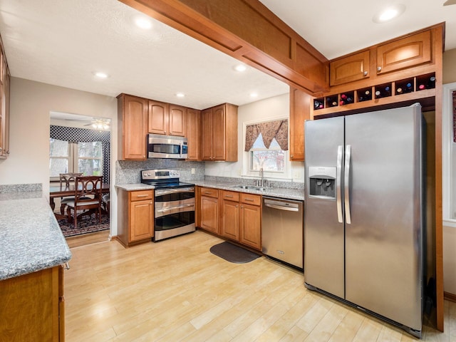 kitchen with backsplash, sink, ceiling fan, light hardwood / wood-style floors, and stainless steel appliances