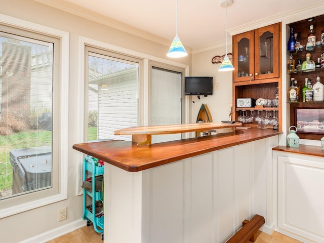 bar featuring pendant lighting, a healthy amount of sunlight, butcher block counters, and crown molding