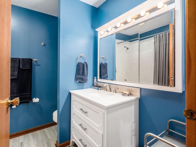 bathroom featuring hardwood / wood-style flooring, vanity, toilet, and walk in shower