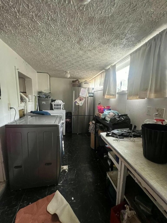 kitchen with a textured ceiling, washer / clothes dryer, and stainless steel refrigerator