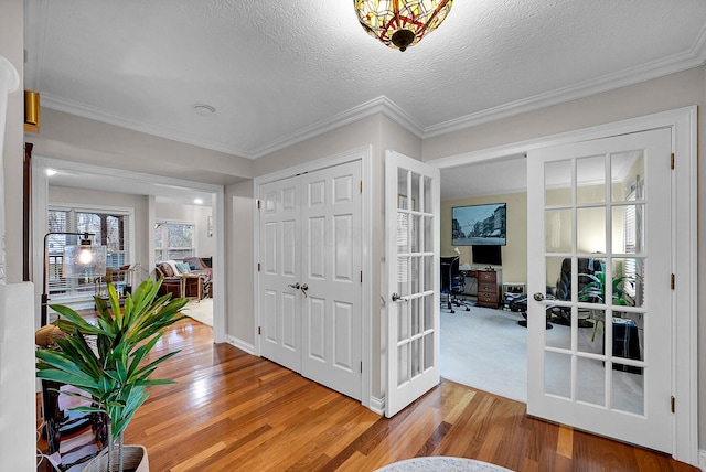 entryway featuring french doors, ornamental molding, a textured ceiling, and hardwood / wood-style flooring