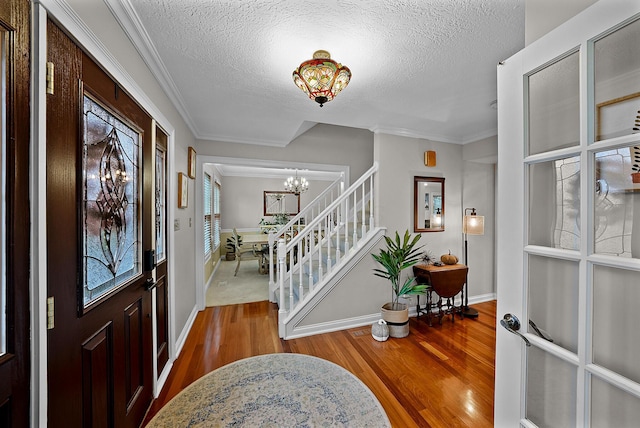 entrance foyer with hardwood / wood-style floors, a notable chandelier, crown molding, and a textured ceiling