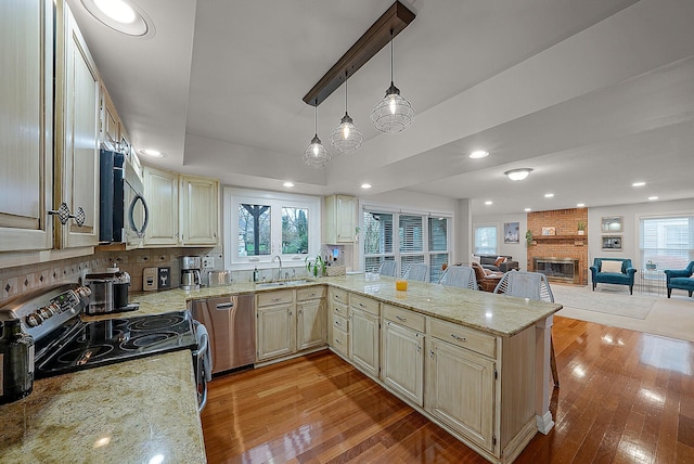 kitchen featuring stainless steel appliances, light hardwood / wood-style flooring, hanging light fixtures, and plenty of natural light