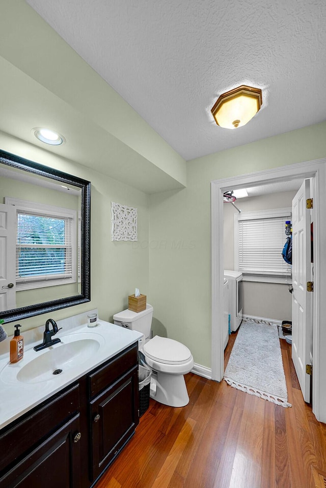 bathroom featuring vanity, washing machine and dryer, wood-type flooring, and a textured ceiling