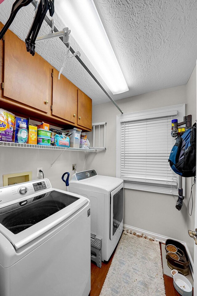 laundry area featuring washer and clothes dryer, dark hardwood / wood-style flooring, cabinets, and a textured ceiling