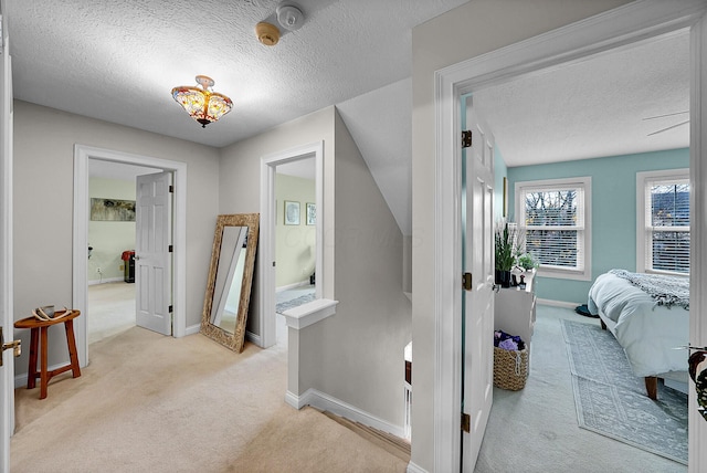 corridor with light colored carpet and a textured ceiling