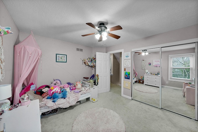 bedroom with a textured ceiling, ceiling fan, and light carpet