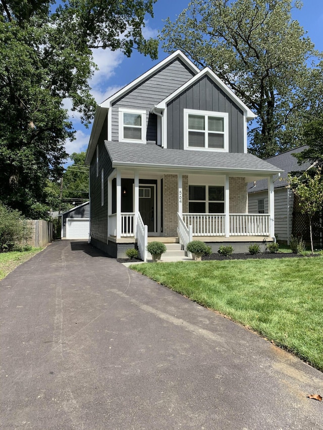 view of front facade with a front yard, a porch, a garage, and an outdoor structure