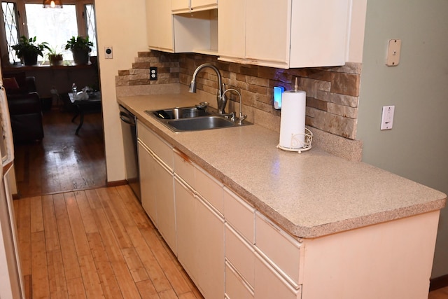 kitchen featuring sink, decorative backsplash, light hardwood / wood-style flooring, and black dishwasher