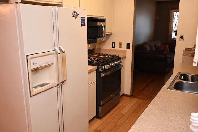 kitchen featuring white cabinetry, sink, light wood-type flooring, and appliances with stainless steel finishes