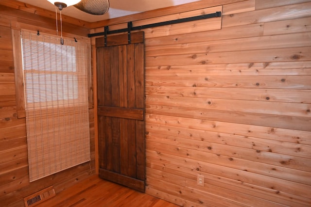 interior space featuring hardwood / wood-style flooring, a barn door, and wooden walls