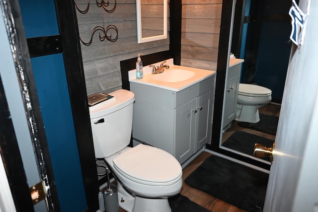 bathroom featuring vanity, wood walls, and toilet