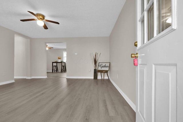 unfurnished living room featuring ceiling fan, light hardwood / wood-style floors, and a textured ceiling