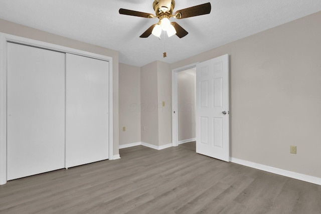 unfurnished bedroom with a closet, a textured ceiling, hardwood / wood-style flooring, and ceiling fan