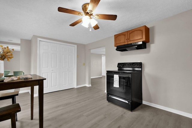 kitchen featuring ceiling fan, black electric range oven, a textured ceiling, and light wood-type flooring