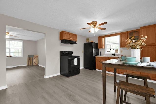 kitchen with black appliances, sink, ceiling fan, a textured ceiling, and light hardwood / wood-style floors