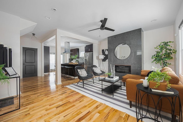 living room featuring hardwood / wood-style floors, ceiling fan, and a fireplace