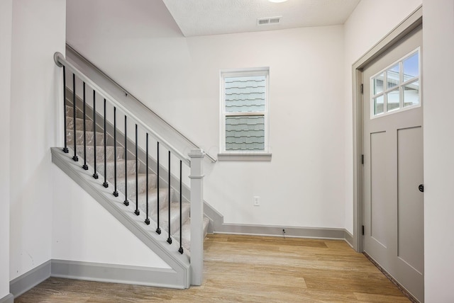 entryway with light hardwood / wood-style flooring and a textured ceiling