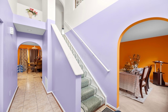 stairway with tile patterned floors and a high ceiling