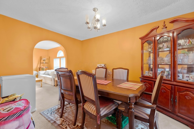 dining space with light colored carpet, a textured ceiling, and an inviting chandelier