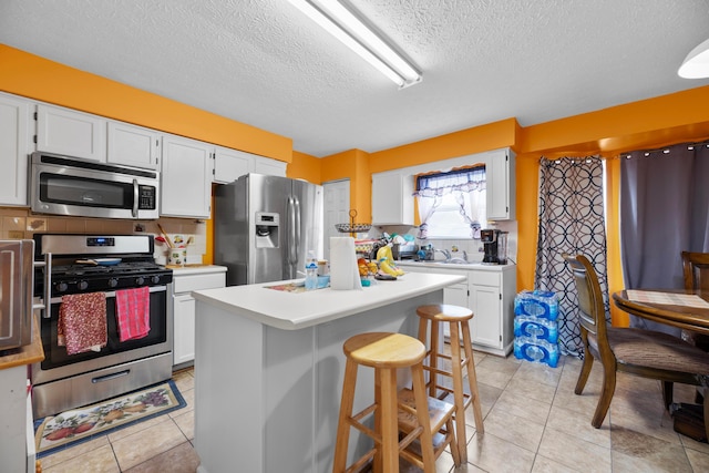 kitchen featuring a kitchen bar, a center island, white cabinets, and stainless steel appliances