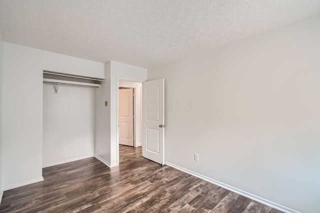 unfurnished bedroom with a textured ceiling, a closet, and dark hardwood / wood-style floors