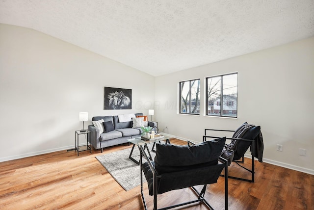 living room with a textured ceiling, vaulted ceiling, and hardwood / wood-style flooring