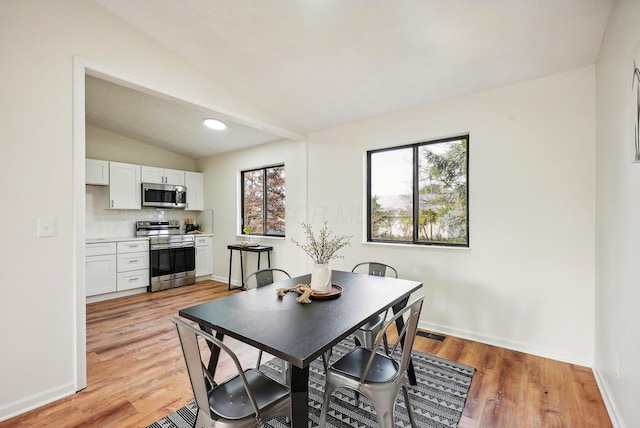 dining area featuring light hardwood / wood-style floors and lofted ceiling