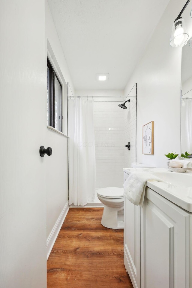 bathroom with hardwood / wood-style floors, vanity, curtained shower, and toilet