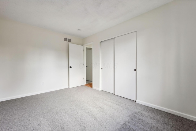 unfurnished bedroom featuring light colored carpet and a closet