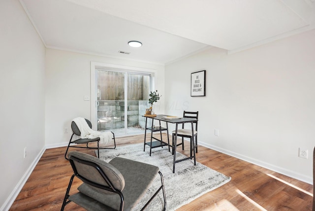 living area with crown molding and hardwood / wood-style flooring