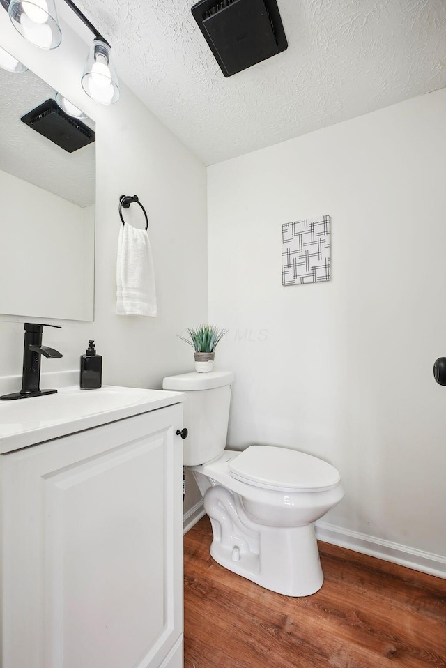 bathroom featuring a textured ceiling, vanity, hardwood / wood-style flooring, and toilet