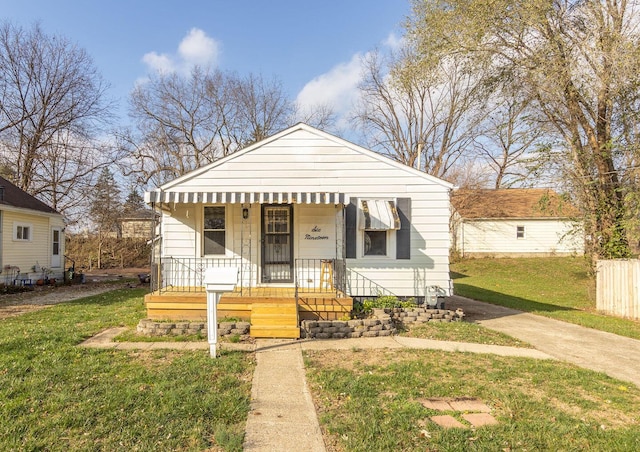 bungalow-style home featuring covered porch and a front lawn