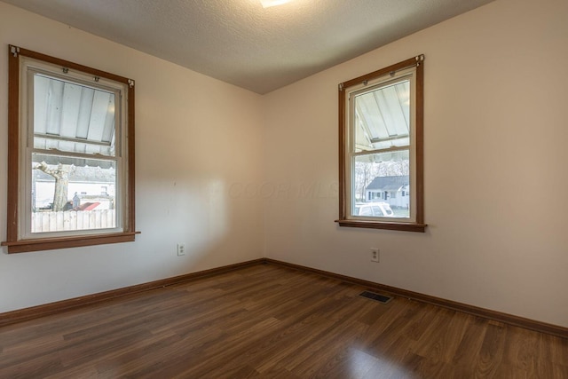 unfurnished room with dark hardwood / wood-style flooring and a textured ceiling