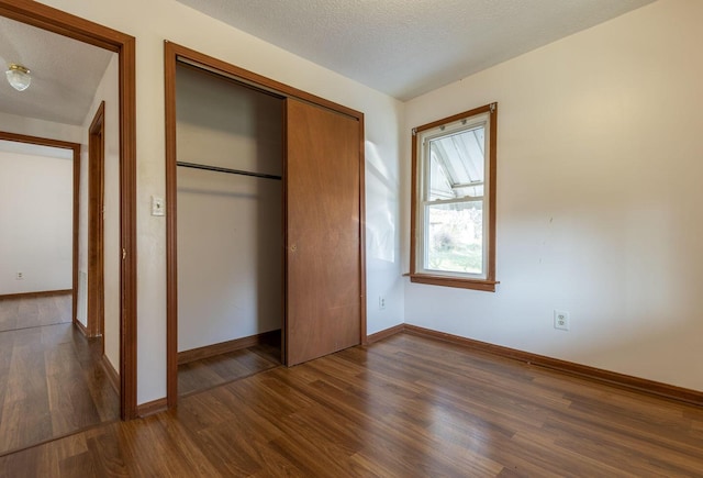 unfurnished bedroom featuring dark hardwood / wood-style flooring, a textured ceiling, and a closet