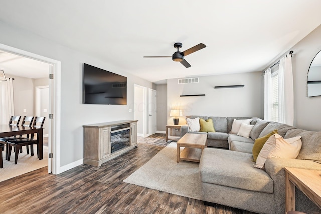 living room with ceiling fan, a fireplace, and dark wood-type flooring