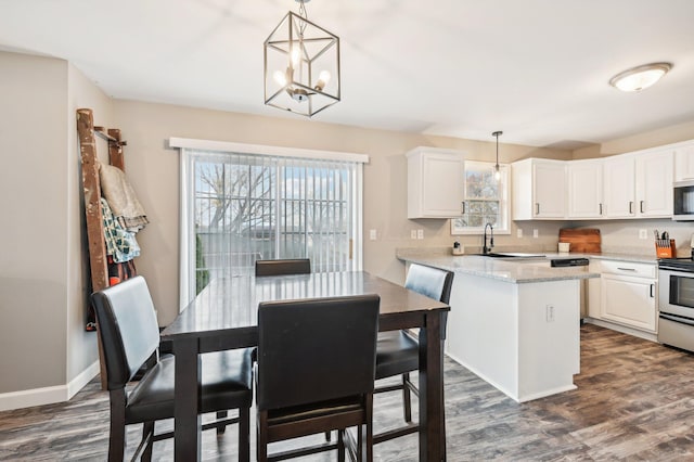 kitchen with dark hardwood / wood-style flooring, a notable chandelier, pendant lighting, white cabinets, and appliances with stainless steel finishes