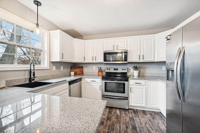 kitchen featuring pendant lighting, dark wood-type flooring, sink, white cabinetry, and stainless steel appliances