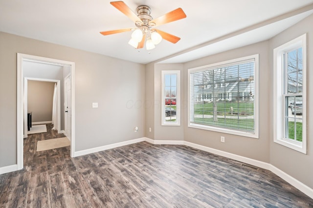 unfurnished room with ceiling fan, dark wood-type flooring, and a healthy amount of sunlight