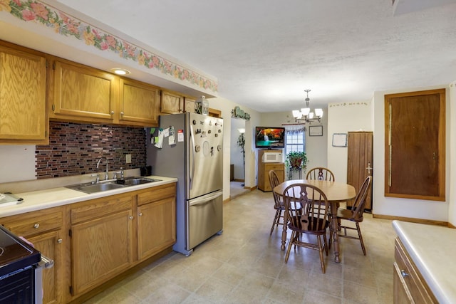 kitchen featuring appliances with stainless steel finishes, pendant lighting, sink, a chandelier, and decorative backsplash