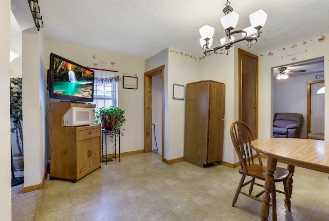 dining area with ceiling fan with notable chandelier and a textured ceiling